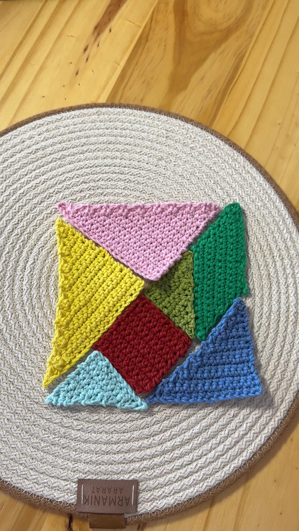 Seven colorful crocheted shapes fitted together into a square tangram